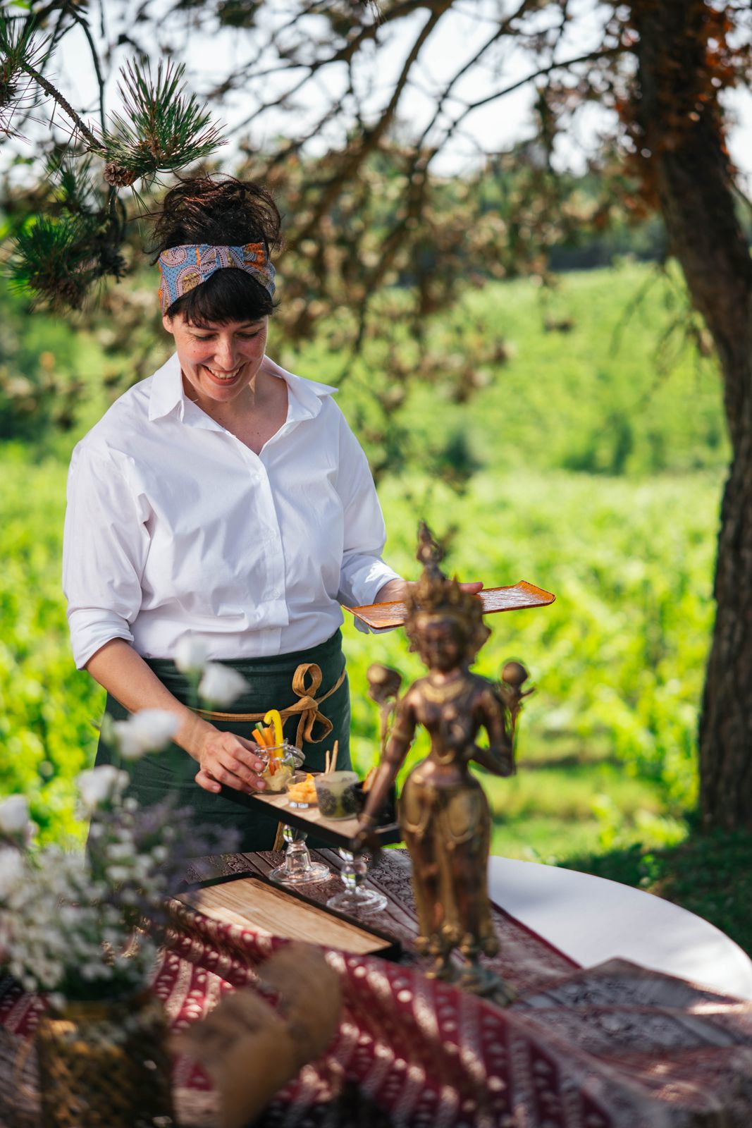 Erica serving finger food at an outdoor table among the vines