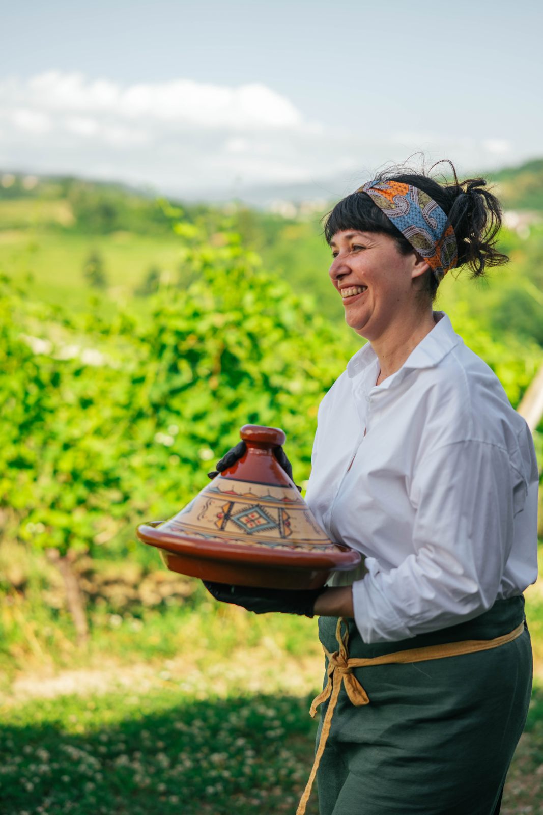 Chef Erica Parpinel smiling as she carries a tajine through the vineyards
