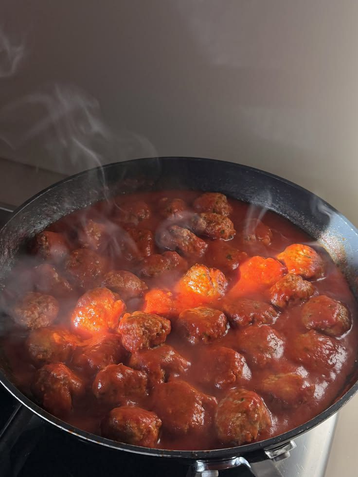 Meatballs simmering in tomato sauce in a pan