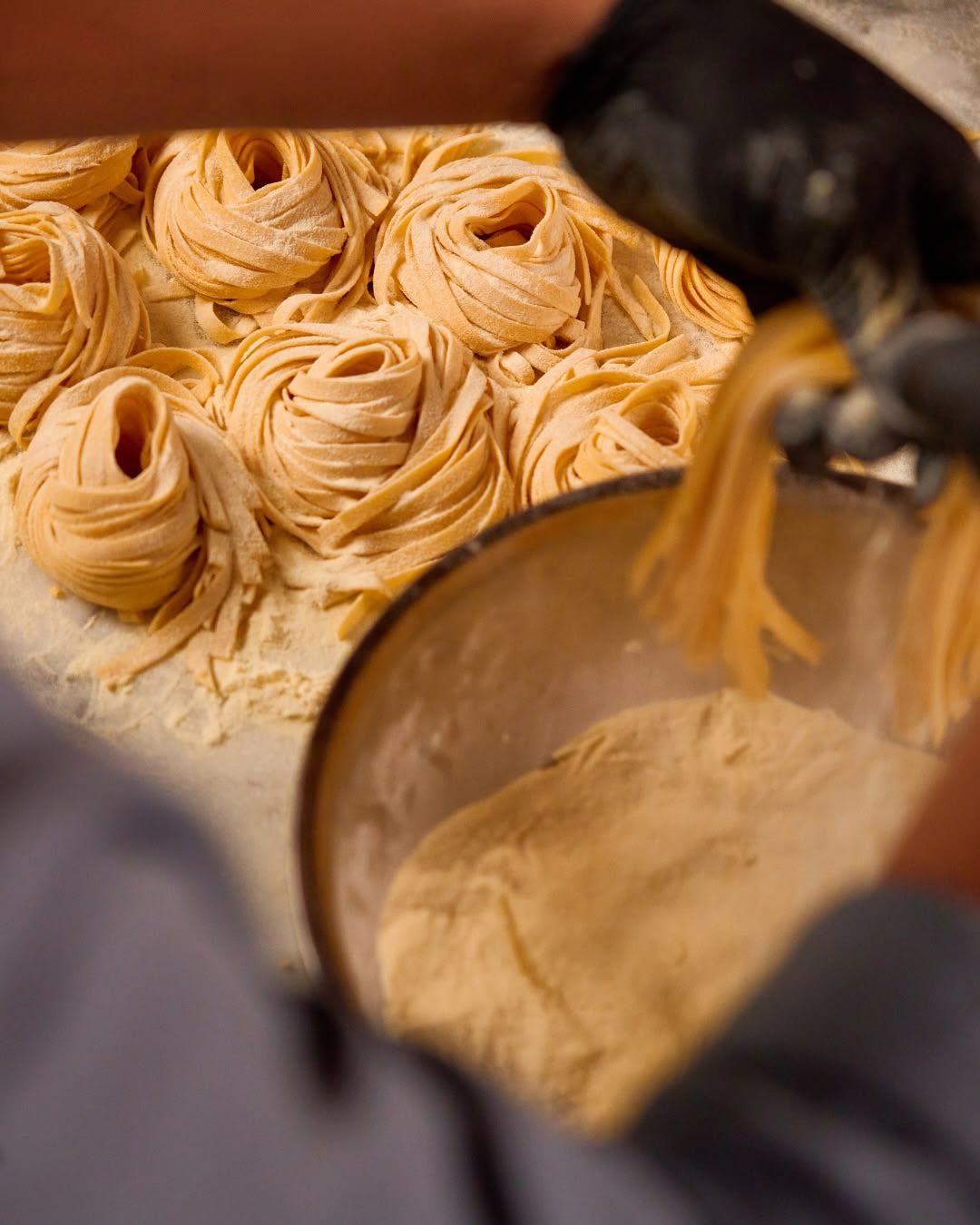Fresh tagliatelle being lifted into a pot