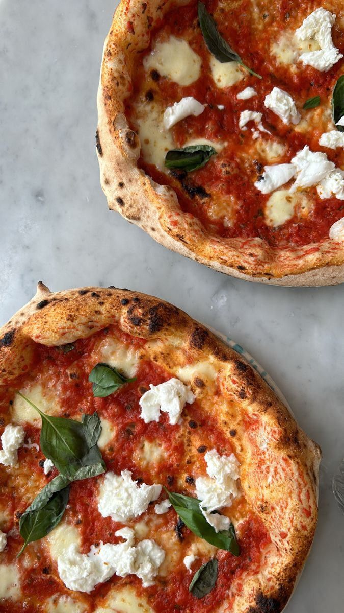 Two Neapolitan-style pizzas with tomato, mozzarella and basil